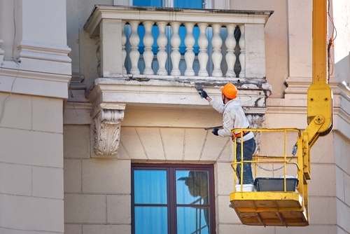 Worker,On,Crane,Repairing,Balcony,,Plastering,Cracked,Stucco,With,Trowel,